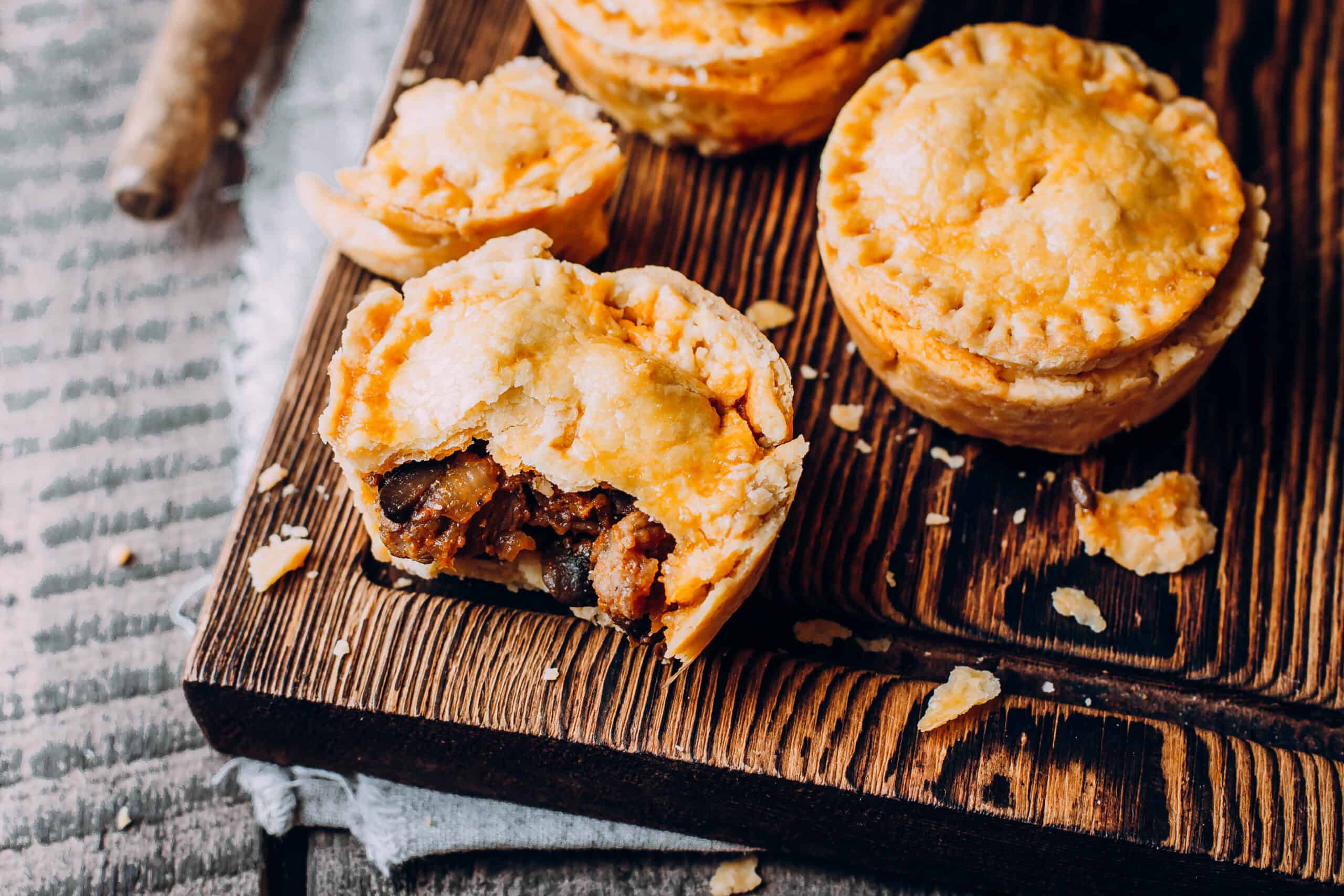 Fresh, traditional Australian meat mini pie on a wooden chopping board